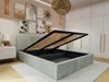 A mint-colored bed with its storage compartment open, revealing the slatted base, in a bedroom setting with artwork on the wall and a wardrobe in the background. Produktbild-Vorschau