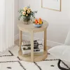 A round side table with two shelves, decorated with a vase of flowers and a bowl of fruit, placed on a patterned rug next to a chair. Podgląd zdjęcia produktu