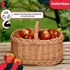 A wicker basket filled with apples sits on a wooden table outdoors, with a blurred green background of trees and foliage. Náhled obrázku produktu