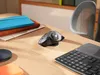 A desk with a Logitech ERGO M575 Trackball mouse, a keyboard, and notebooks. Anteprima dell’immagine prodotto