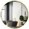 A modern bathroom with a freestanding bathtub, herringbone tile wall, and a round LED mirror.