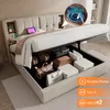 A bed with its storage compartment open, showing various items stored inside, and a close-up inset of a phone charging wirelessly. Produktbild-Vorschau