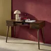 A wooden desk with a lamp, decorative cherries, and a magazine on it, set against a textured red wall. Anteprima dell’immagine prodotto