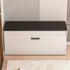 A white shoe cabinet with a black top and a single drawer, set against a striped wall. Podgląd zdjęcia produktu