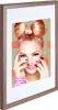 A framed picture of a woman with a bow-shaped hairstyle and bright makeup, set against a polka-dot background. Produktbild-Vorschau