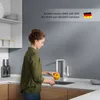 A woman is washing a yellow tomato under a modern white kitchen faucet. Podgląd zdjęcia produktu
