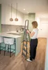 A woman is using a stepladder in a modern kitchen. Anteprima dell’immagine prodotto