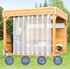 An outdoor gazebo with white curtains, a grill, and seating, set in a grassy yard with trees in the background. Produktbild-Vorschau