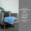 A blue fleece blanket draped over a gray armchair, with a dark gray cushion and a green plant in the background. Text is overlaid on the right side. Náhľad obrázku produktu