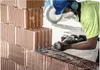 A construction worker is using a reciprocating saw to cut through hollow bricks. Voir les images du produit