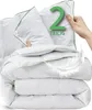 A stack of white duvets with green trim, with a hand holding one of them and a large green number '2' and text 'TEILIG' overlaid. Produktbild-Vorschau