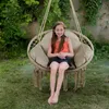 A young girl sits in a hanging chair in a garden. Voir les images du produit