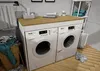 A laundry room scene with a washing machine and dryer unit, laundry basket, and towels. Náhled obrázku produktu