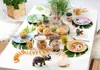 A table set for a children's party with a zoo/safari theme, featuring plates, cups, muffins, and animal figurines. Anteprima dell’immagine prodotto