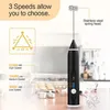 A black electric milk frother is displayed on a kitchen counter with illustrative diagrams and text highlighting its features. Produktbild-Vorschau
