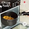 A pot with food inside is being placed into an oven. Produktbild-Vorschau