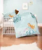 A baby crib with bedding featuring a princess and unicorn theme, with a teddy bear peeking out from behind a pillow. Anteprima dell’immagine prodotto