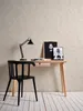A minimalist desk setup with a chair, lamp, and artwork. Produktbild-Vorschau