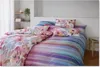 A neatly made bed with colorful striped and floral patterned bedding. Produktbild-Vorschau