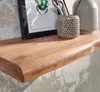 A close-up view of a wooden shelf with a live edge, displaying a framed picture of a beetle, a decorative pot with scissors and pencils, and a vase. Náhled obrázku produktu