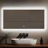 A modern bathroom vanity with a large LED mirror, a sink, and a soap dispenser.