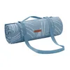 A rolled-up picnic blanket with a blue and white pattern and a brown logo tag. Produktbild-Vorschau