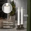 Two LED candles in holders on a windowsill with a small Christmas tree and fairy lights in the background. Podgląd zdjęcia produktu