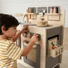 A young boy is playing with a wooden toy kitchen. Podgląd zdjęcia produktu
