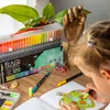 A young girl is coloring a picture of a turtle with marker pens, with a set of marker pens and a wooden hand model in the background. Produktbild-Vorschau