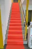 A red carpet runner on a staircase with yellow railings. Produktbild-Vorschau