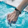 A person's arm wearing a smartwatch is submerged in water, with splashes around it. Produktbild-Vorschau