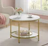 A round coffee table with a marble-like top and gold legs, placed in a living room setting. There is a vase with flowers and a teacup on the table, and a throw blanket on a nearby chair. Produktbild-Vorschau