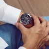 A person wearing a white shirt and blue jeans, showing off a silver watch on their wrist. Produktbild-Vorschau