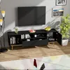 A modern living room scene featuring a black TV stand with golden legs, a television mounted on the wall, a floor lamp, and decorative items. Produktbild-Vorschau