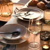 A table setting with plates, cutlery, wine glasses, and candles. Produktbild-Vorschau