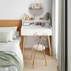 A white vanity desk with a round mirror and a gold chair in a bedroom setting. Produktbild-Vorschau