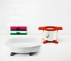A kitchen counter with a white ceramic dish, a stack of colorful coasters, and a stainless steel pot with a red trivet. Anteprima dell’immagine prodotto