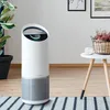 An air purifier is shown in a well-lit living room setting, next to a plant and a small table with decorative items. Anteprima dell’immagine prodotto