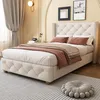 A bedroom scene with a tufted bed, curtains, and wall decor.