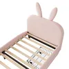 A close-up view of a pink upholstered bed frame with wooden slats and black wire storage baskets underneath. Anteprima dell’immagine prodotto