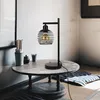 A black metal table lamp with a vintage Edison bulb sits on a round wooden table in a room with tatami flooring. Podgląd zdjęcia produktu