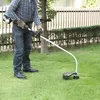 A person is using a string trimmer in a grassy yard. Produktbild-Vorschau