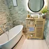 A modern bathroom with a freestanding bathtub and a bamboo storage unit. Produktbild-Vorschau