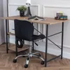 A black office chair is placed in front of a wooden desk with a plant, lamp, and books on it. The scene is set in a room with white paneled walls and a wooden floor. Produktbild-Vorschau