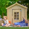 Two children are playing in front of a wooden playhouse in a garden. Anteprima dell’immagine prodotto