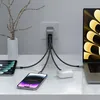 A Satechi USB-C 4-port GaN travel charger is plugged into a wall outlet, powering a laptop, tablet, smartphone, and wireless earbuds. Náhled obrázku produktu