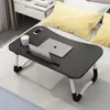 A foldable lap desk is placed on a bed with a laptop, a phone, and a cup on it. Anteprima dell’immagine prodotto