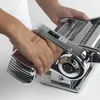 A person's hands are operating a chrome pasta maker. Podgląd zdjęcia produktu