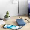 A blue power bank is charging a smartphone on a wooden desk, with a small potted cactus and a laptop in the background. Produktbild-Vorschau