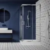 A modern bathroom with a blue tiled wall, a shower cabin, a sink, and patterned floor tiles. Produktbild-Vorschau